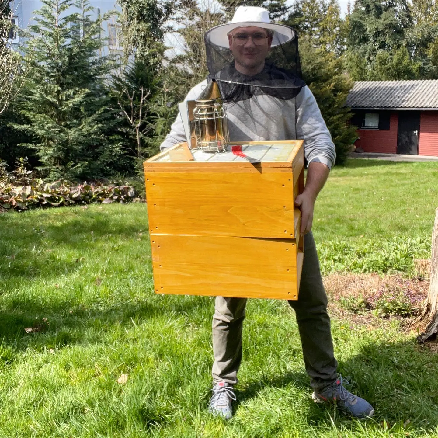Christoph mit Schutzschleier, Beute und Smoker in seiner Imkerei
